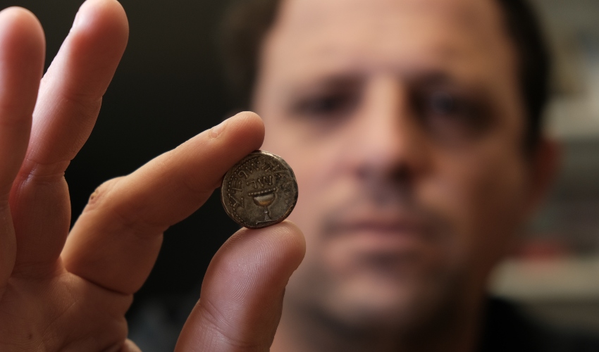 אילן חדד, המפקח על הסחר ברשות העתיקות עם מטבע שקל ישראל קדום (צילום: אמיל אלג'ם, רשות העתיקות)